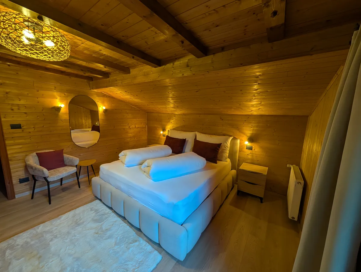 Camera da letto con lampada a sospensione intrecciata, specchio ovale, applique a parete e una poltrona accanto al letto